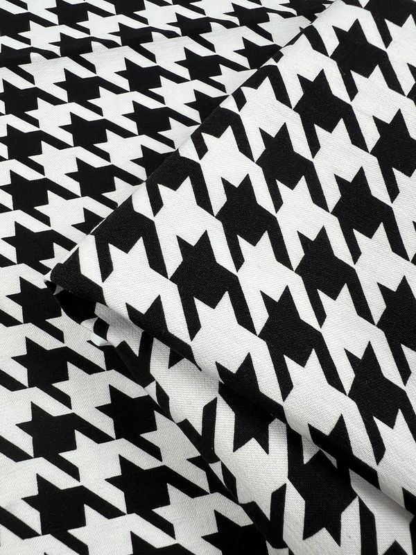 Close-up of Super Cheap Fabrics' Printed Bengaline - Grande Houndstooth (150cm). The black and white geometric shapes align closely, with one piece folded over another, highlighting the textured look of this medium-weight fabric.
