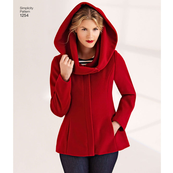 A woman in a vibrant red hooded coat, made from the Simplicity S1254 Leanne Marshall pattern by Super Cheap Fabrics, stands against a light background. Her blonde hair and striped shirt complete this stylish winter look.