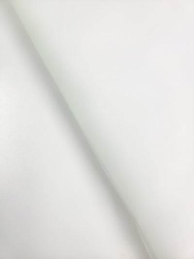 A close-up of Super Cheap Fabrics' Soft Tulle - White (150cm), draped diagonally, displays subtle shadows and a soft texture across its smooth surface, perfect for costumes or elegant bridal veils.
