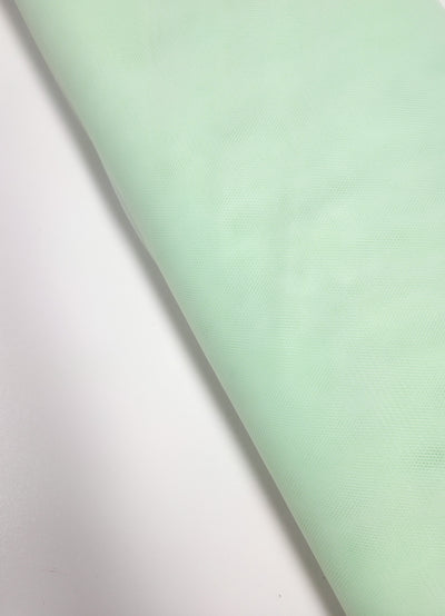 Super Cheap Fabrics’ Soft Tulle - Patina Green - 150cm is a soft, subtly textured and slightly translucent fabric, ideal for bridal veils or costumes. Shown here partially unrolled on a white surface.