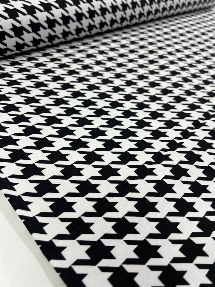 The Printed Bengaline - Grande Houndstooth by Super Cheap Fabrics is a black and white medium-weight fabric with a classic houndstooth pattern and geometric design, featuring two-way stretch for versatile wear.