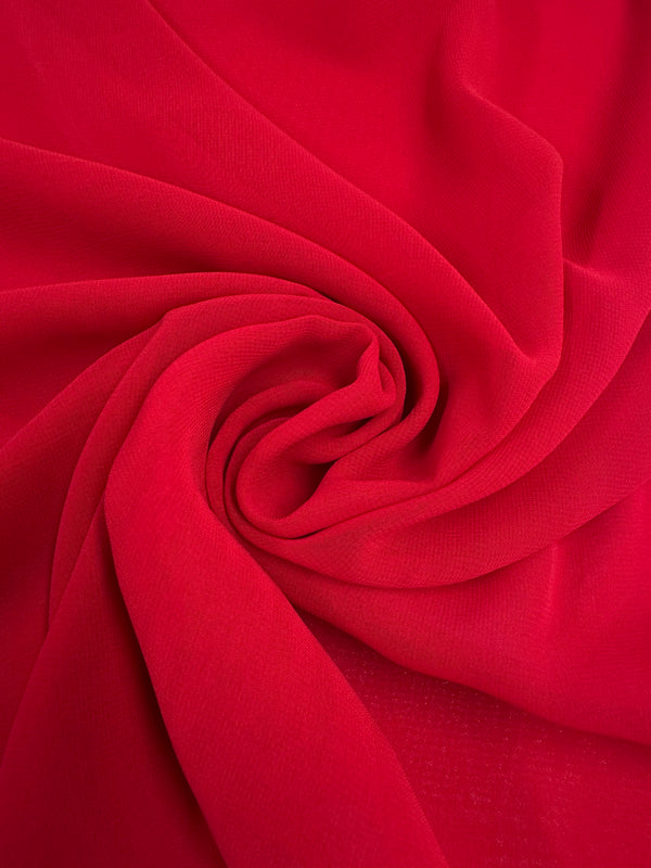 The Hi-Multi Chiffon - Red from Super Cheap Fabrics, measuring 150cm, features an artistic swirling pattern with vibrant red chiffon that forms a spiral effect, showcasing its lightweight texture for a dynamic and elegant appearance.