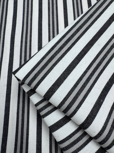 Close-up of Super Cheap Fabrics’ Cotton Drill - Allsorts (147cm): the folded black and white striped cotton fabric showcases a durable diagonal weave, enhancing the striking pattern with varying thickness.