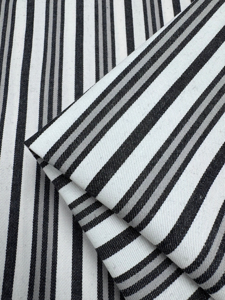 Close-up of Super Cheap Fabrics’ Cotton Drill - Allsorts (147cm): the folded black and white striped cotton fabric showcases a durable diagonal weave, enhancing the striking pattern with varying thickness.