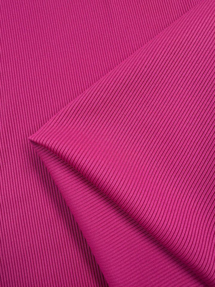 Close-up of the Super Cheap Fabrics Rib Knit in Hot Pink (130cm), showcasing its vibrant color, textured surface, and generous stretch in an overlapping pattern.