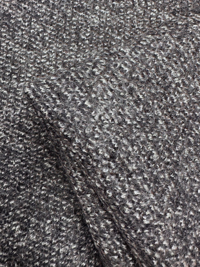 A close-up of Super Cheap Fabrics' Boiled Wool - Lamé Charcoal Marle - 150cm shows its softly bumpy, textured gray boucle pattern. The thick weave and subtle color variations enhance the heavy weight fabric's look.