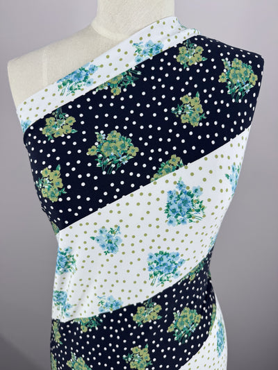 A mannequin displays Super Cheap Fabrics' Printed Lycra - Tea Party - 150cm, featuring medium-weight Polyester/Spandex with diagonal stripes of navy and white polka dots, floral clusters, green, and blue floral designs.