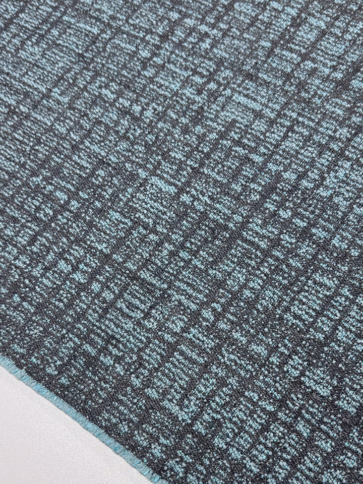 Close-up of Super Cheap Fabrics' "Upholstery - Dexter 37 - 147cm" carpet with a gray and blue pattern of interwoven lines and squares, similar to heavy weight upholstery fabric. The diagonal angle highlights its intricate detail.