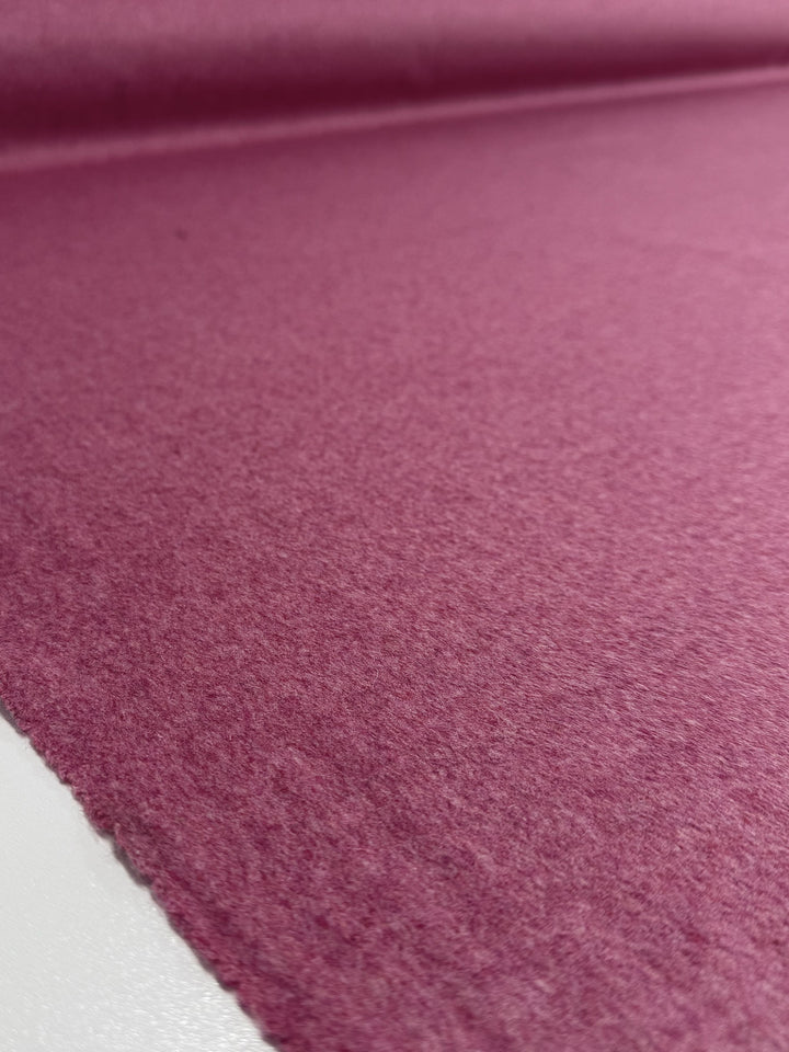 Close-up of Super Cheap Fabrics’ Wool Cashmere - Wild Rose (150cm), showing its soft, textured pink surface and slightly fuzzy finish as the premium material extends into the background.