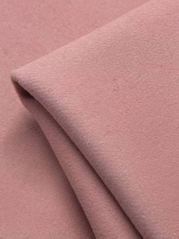 Close-up of a folded piece of Super Cheap Fabrics' Wool Cashmere in Coral Cloud - 150cm, displaying luxurious softness with a smooth texture and gentle folds that highlight its plush appearance.
