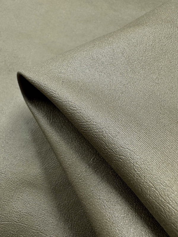 A close-up of a folded piece of Super Cheap Fabrics' Faux Spandex Leather in Tea Leaf color reveals its soft, textured, medium-weight surface with a slight sheen that captures light beautifully.