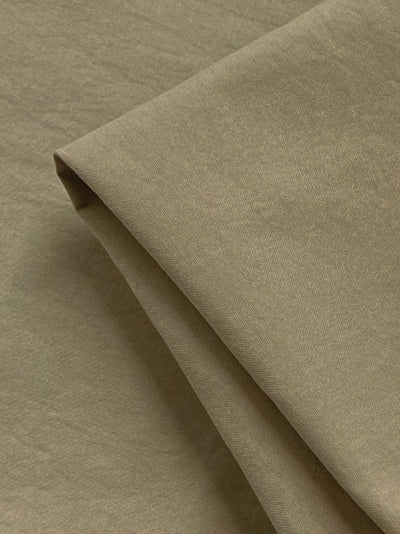 Close-up of Super Cheap Fabrics' Canvas - Pale Khaki - 136cm, highlighting its slightly textured surface. The lightweight polyester is neatly arranged, showcasing a smooth and uniform texture.