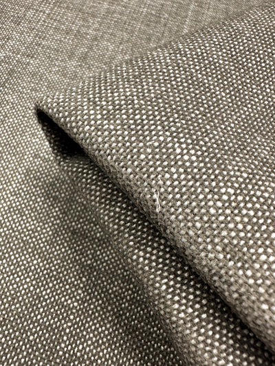 A close-up view of Super Cheap Fabrics' Upholstery - Shitake - 142cm showcases its textured grey and white woven design in a modern minimalist style with a small square pattern. A fold highlights the plain weave detail and thickness.