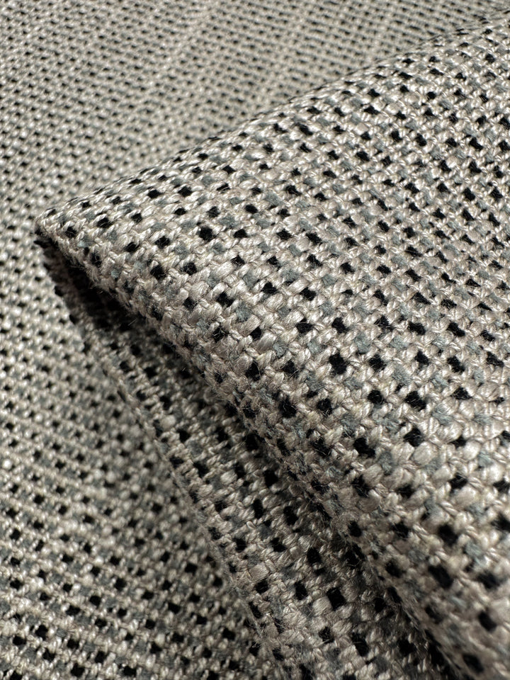 The Upholstery Logan - Rhino from Super Cheap Fabrics, sized at 145cm, showcases a heavy-weight, detailed woven texture in grey and black with a small check pattern. Ideal for adding textured accents.