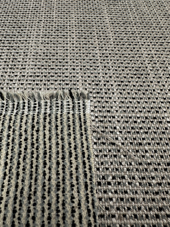 Close-up of Super Cheap Fabrics' Upholstery Logan - Rhino - 145cm, displaying textured gray open-weave grid with small raised dots and a square cutout revealing the heavy weight's striped underside.