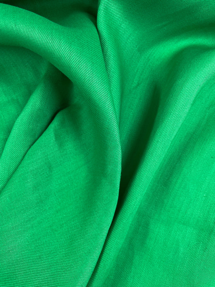 A close-up of the vibrant green Pure Washed Linen - Jelly Bean by Super Cheap Fabrics, featuring lightweight, soft folds and a smooth texture perfect for crafting elegant garments. Width: 140cm.