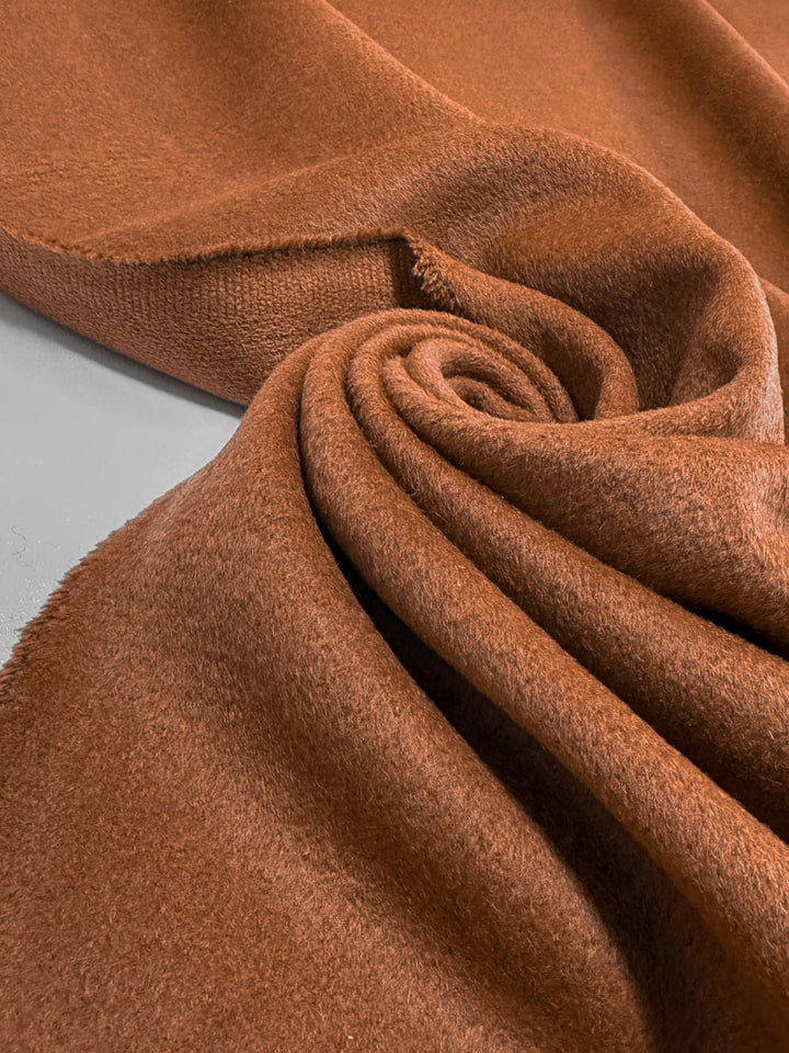 A close-up reveals the luxurious, fuzzy texture of Super Cheap Fabrics’ Wool Cashmere - Dark Hazel - 150cm, artfully swirled on a flat surface.