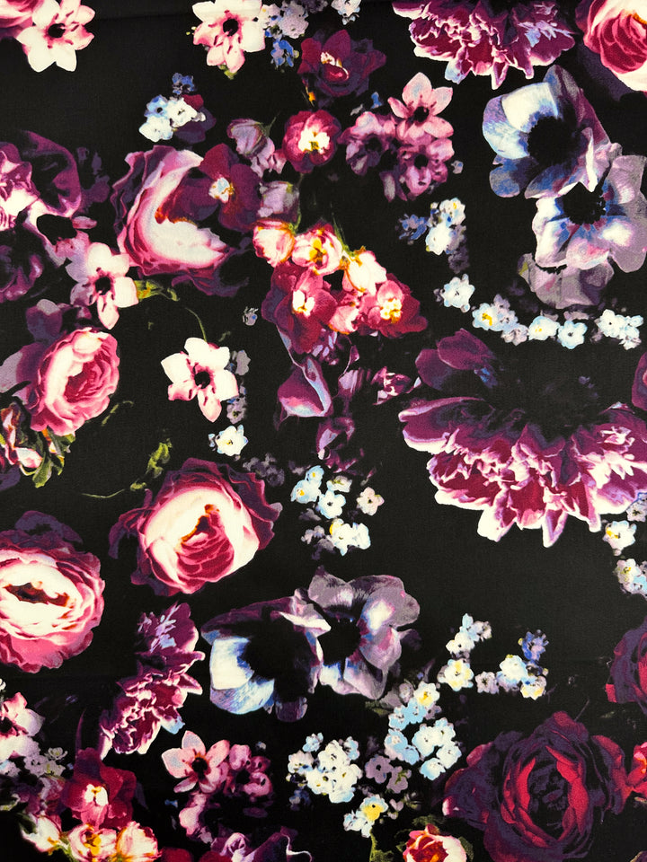 The Cotton Sateen - Arrangement - 125cm by Super Cheap Fabrics features a bold floral pattern with pink, purple, and white blossoms on black. The vibrant roses and various flowers create a striking design on soft cotton dresses ideal for any occasion.