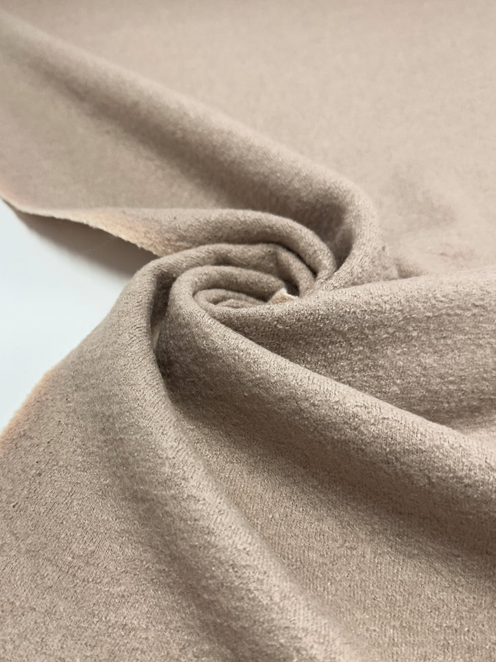 Close-up of Super Cheap Fabrics' Boiled Wool in White Pepper, 142cm wide. The soft fabric spirals into folds and shadows, showcasing its smooth texture and cozy appeal—ideal for heavy-weight clothing or home decor.