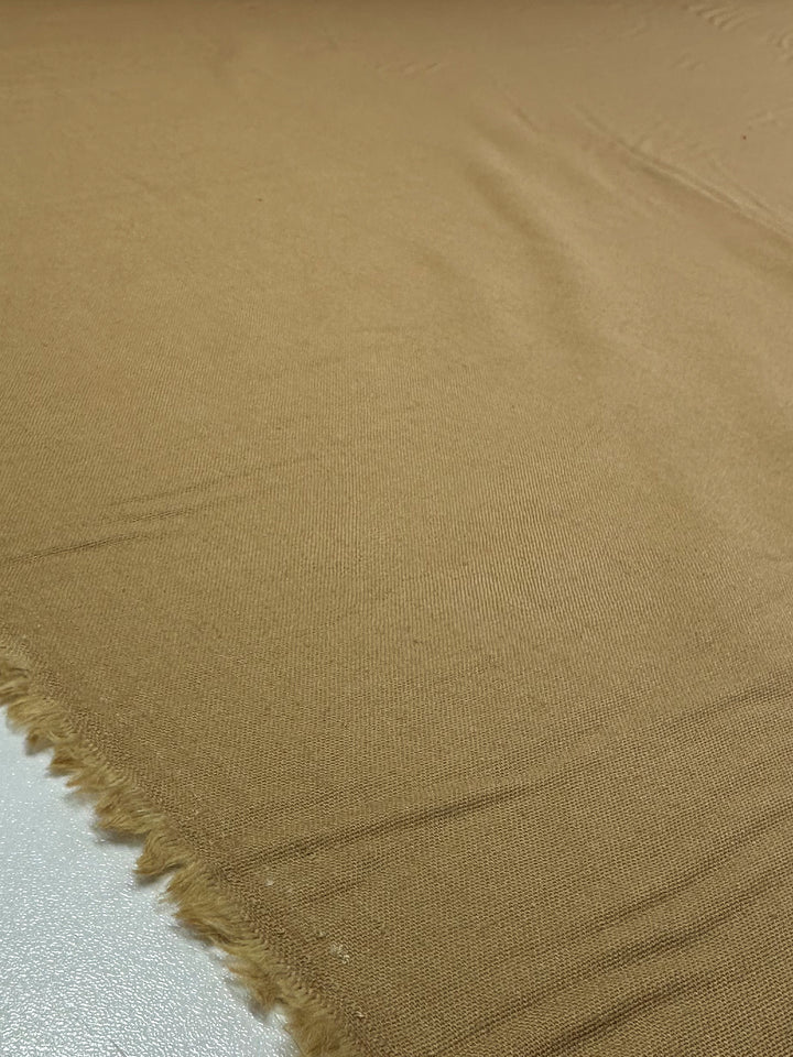A close-up of Super Cheap Fabrics' Linen Blend - Dijon captures its light brown medium weight with fringed edges, smooth yet slightly textured surface in rich Dijon hues.
