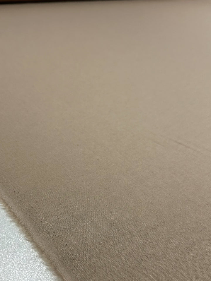 Close-up of a large roll of Super Cheap Fabrics' 135cm Linen Blend in Oxford Tan, laid flat to display its smooth texture and unfinished edge.