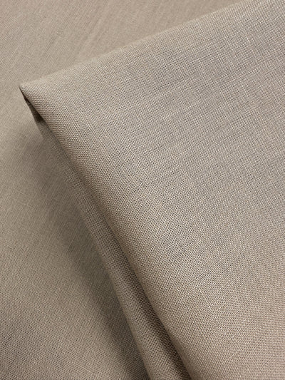 Close-up of a folded piece of Linen Blend - Oxford Tan from Super Cheap Fabrics. The 135cm fabric's visible weave gives it a soft yet sturdy appearance, neatly arranged with sharp, defined edges.