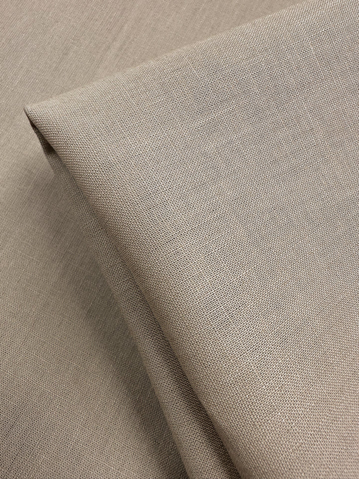Close-up of a folded piece of Linen Blend - Oxford Tan from Super Cheap Fabrics. The 135cm fabric's visible weave gives it a soft yet sturdy appearance, neatly arranged with sharp, defined edges.
