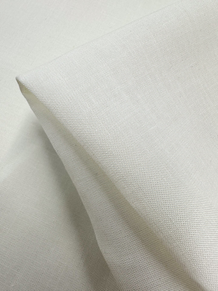 A close-up of Super Cheap Fabrics' Pure Linen in Ivory, 145cm wide, neatly folded to highlight its lightweight, subtle woven texture. The breathable material appears smooth and plain, occupying the entire frame.