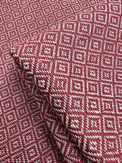 Close-up of Geometric Diamond Weave Upholstery in red and white by Super Cheap Fabrics, Windermere - 142cm, displays a raised diamond weave pattern. Fabric is folded to highlight intricate design.