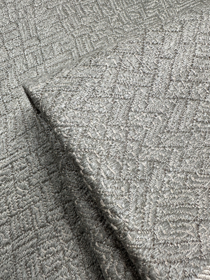 Close-up of Super Cheap Fabrics' Herringbone Textured Upholstery in Urbane Silver, 143cm wide, featuring a sophisticated raised crosshatch design with a shimmering metallic finish.