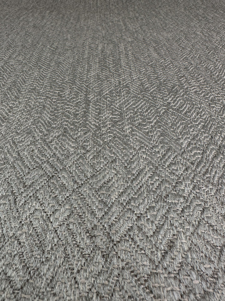 A close-up of Super Cheap Fabrics' Urbane Silver showcases its intricate herringbone pattern, adding depth and movement to this heavy-weight upholstery fabric with its textured grey surface.
