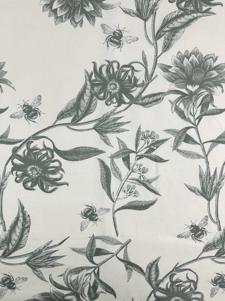 The "Bee Seagrass" by Super Cheap Fabrics features a light background with bees and blooming flowers adorned with elongated leaves. This intricate pattern, ideal for home décor, is a monochromatic blend of green shades on medium-weight cotton duck fabric at 150cm.
