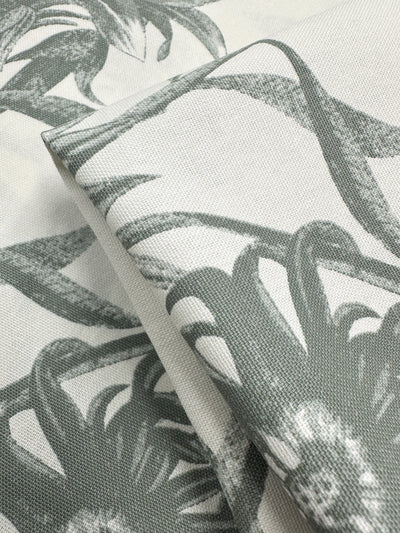 A close-up of the textured Cotton Duck - Bee Seagrass fabric by Super Cheap Fabrics reveals a medium-weight monochrome botanical pattern, featuring detailed gray leaves and flowers, perfect for an elegant home décor look against a light background.