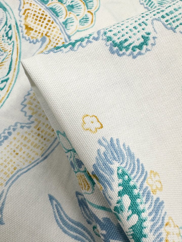 Close-up of folded Cotton Duck - Fine Lines by Super Cheap Fabrics, featuring a floral and abstract motif in teal, mustard yellow, and light blue on white. The medium weight texture highlights intricate design details perfect for a vibrant and artistic home décor look. Width: 147cm.