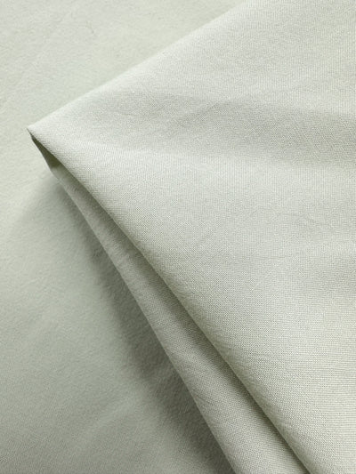 A close-up shows a neatly folded light gray fabric with fine, even weaves and a smooth texture. The lightweight cotton from Super Cheap Fabrics, named "Fairest Jade," is 152cm wide with a soft, matte finish.