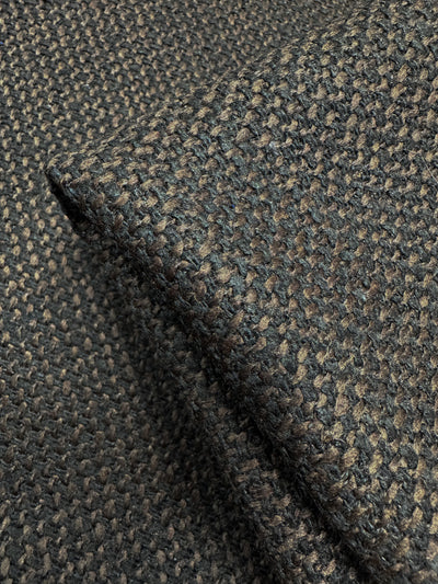 The Designer Tweed - Choco by Super Cheap Fabrics features a close-up of a textured, woven design in black and brown. This heavy weight fabric appears thick and folded, showcasing its intricate texture and color variations—perfect for crafting durable outer coats. Width: 150cm.