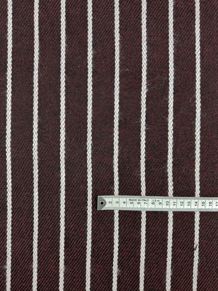 The Designer Tweed - Plum Line by Super Cheap Fabrics is a heavy-weight, herringbone fabric with vertical white stripes, ideal for outer coats. It’s shown with a metal measuring tape across its 155cm width to highlight scale.