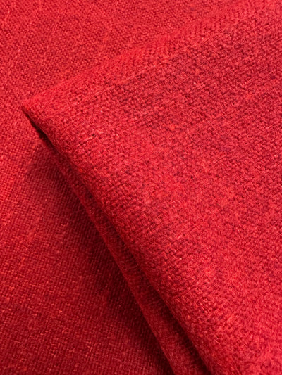 Close-up of a folded Brushed Tweed - Flame fabric from Super Cheap Fabrics. The heavy, slightly textured textile features a uniform scarlet color and visible weave, suggesting coziness and warmth. Width: 150cm.