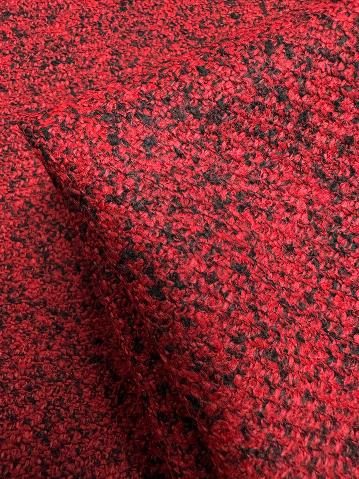 The Designer Tweed - Serpents by Super Cheap Fabrics features a close-up of red and black textured fabric with a looped woven pattern. Perfect for outer coats, this heavyweight polyester is thick, soft, and radiates warmth and comfort with its intricate design and vibrant colors. Width: 150cm.