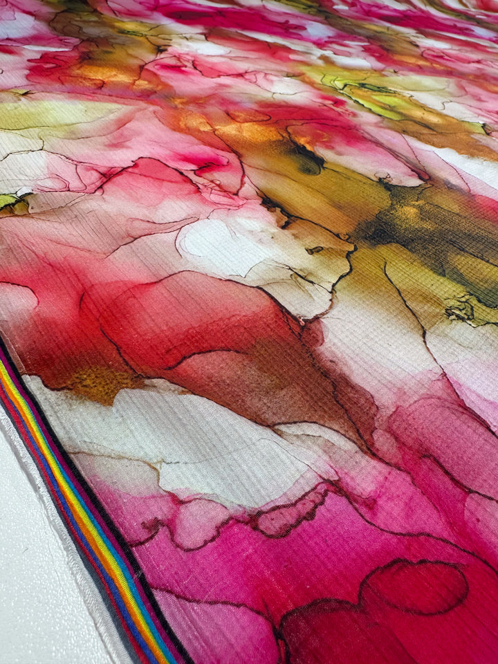 Close-up of a vibrant, abstract design on Super Cheap Fabrics' Designer Cotton - Catalina. The 150cm canvas features fluid red, pink, brown, and white shapes resembling marbled patterns with a multicolored striped border.