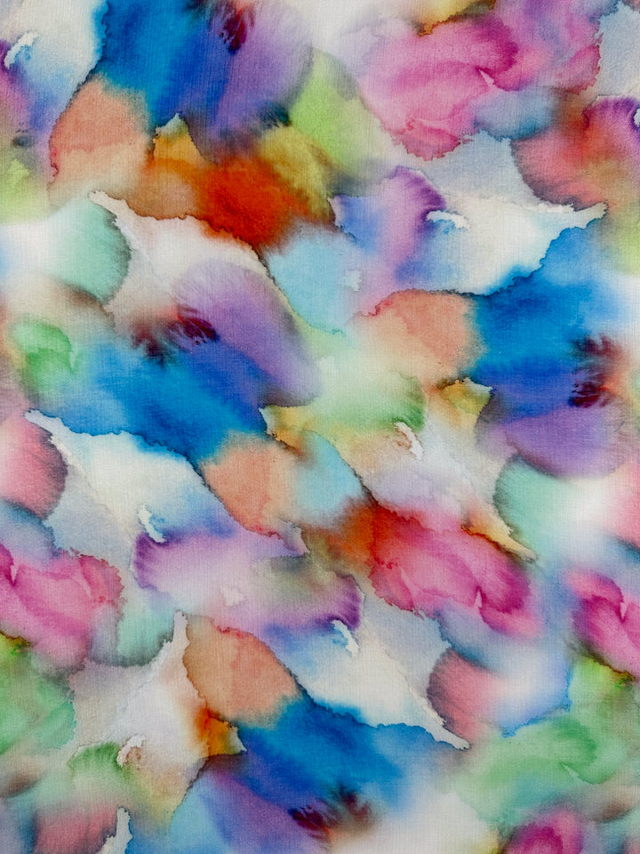 The Designer Cotton - Airbrush from Super Cheap Fabrics, at 150cm wide, features a soft, cloud-like watercolor design with vibrant colors such as blue, pink, green, and orange that create a calming, dreamlike appearance for luxury sewing projects.