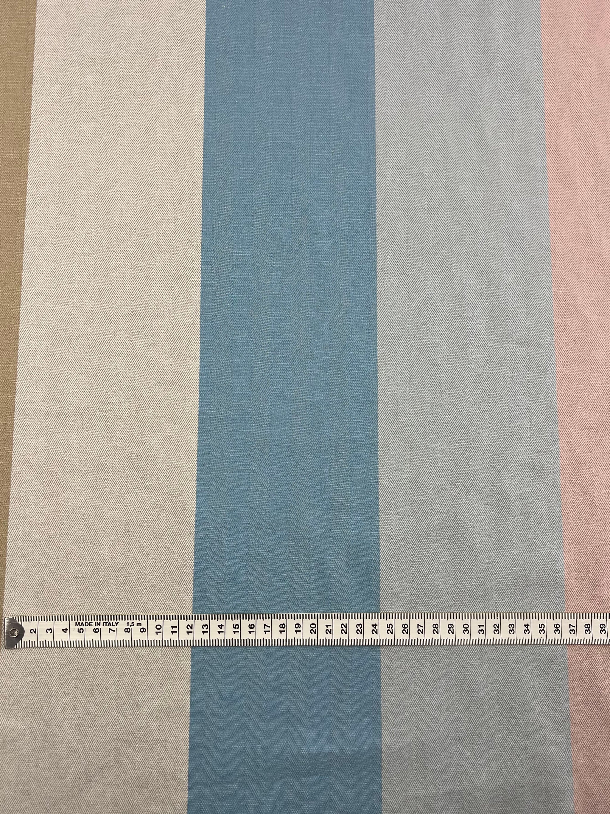 A fabric with vertical stripes in beige, white, blue, light blue, and pink is laid flat. A measuring tape, extended and slightly curved, stretches horizontally across the Designer Cotton - Blipe - 155cm from Super Cheap Fabrics and measures 20 inches. Crafted from sustainable deadstock materials for eco-friendly fashion lovers.