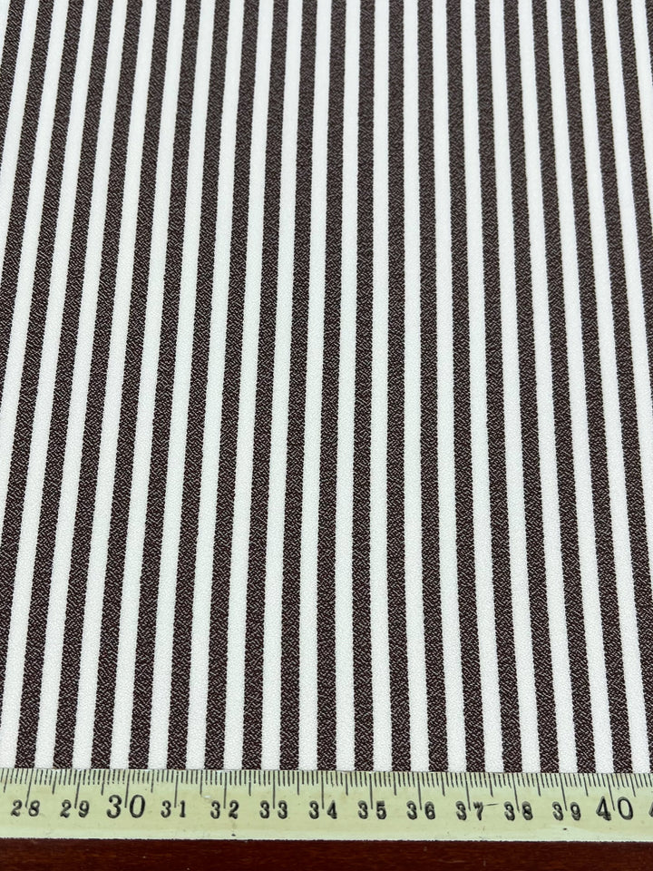 Super Cheap Fabrics’ Striped Crepe - Fondue Fudge (150cm) features black and white vertical stripes on lightweight polyester, shown with a measuring tape from 28–41cm—perfect for stylish eveningwear.