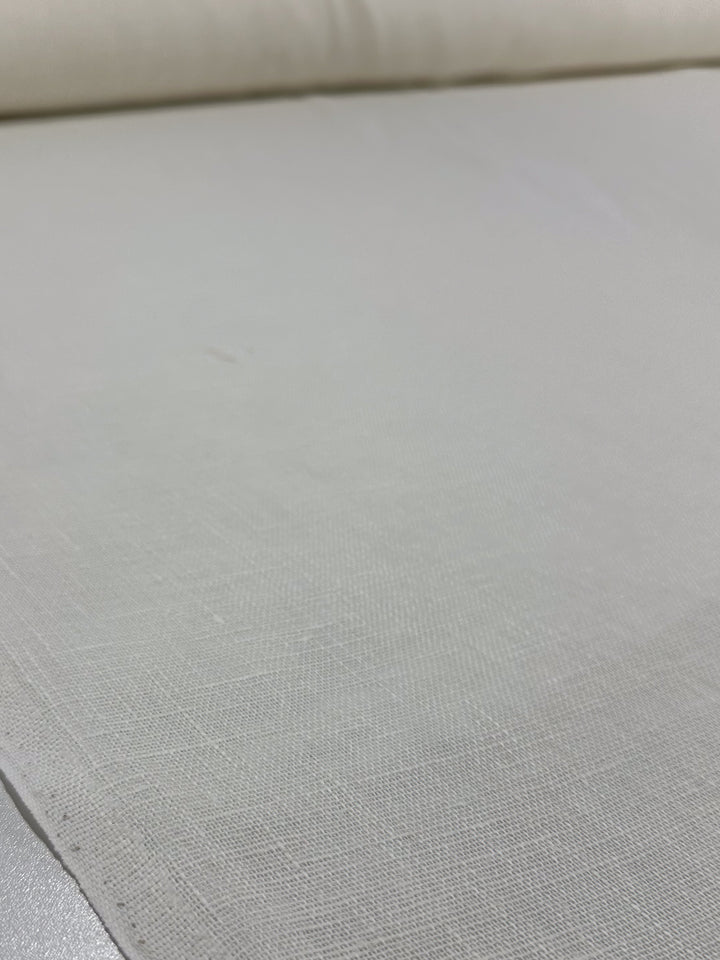 A close-up of Super Cheap Fabrics' Loose Weave Pure Linen - Off White (150cm), spread out to highlight its breathable texture and subtle weave pattern.