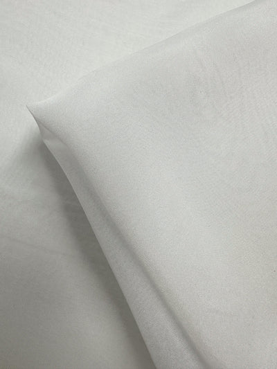 A close-up of Super Cheap Fabrics’ Pure Silk Chiffon in Ivory (140cm), folded to highlight its soft texture and lightweight, semi-sheer quality—ideal for spring and summer garments.