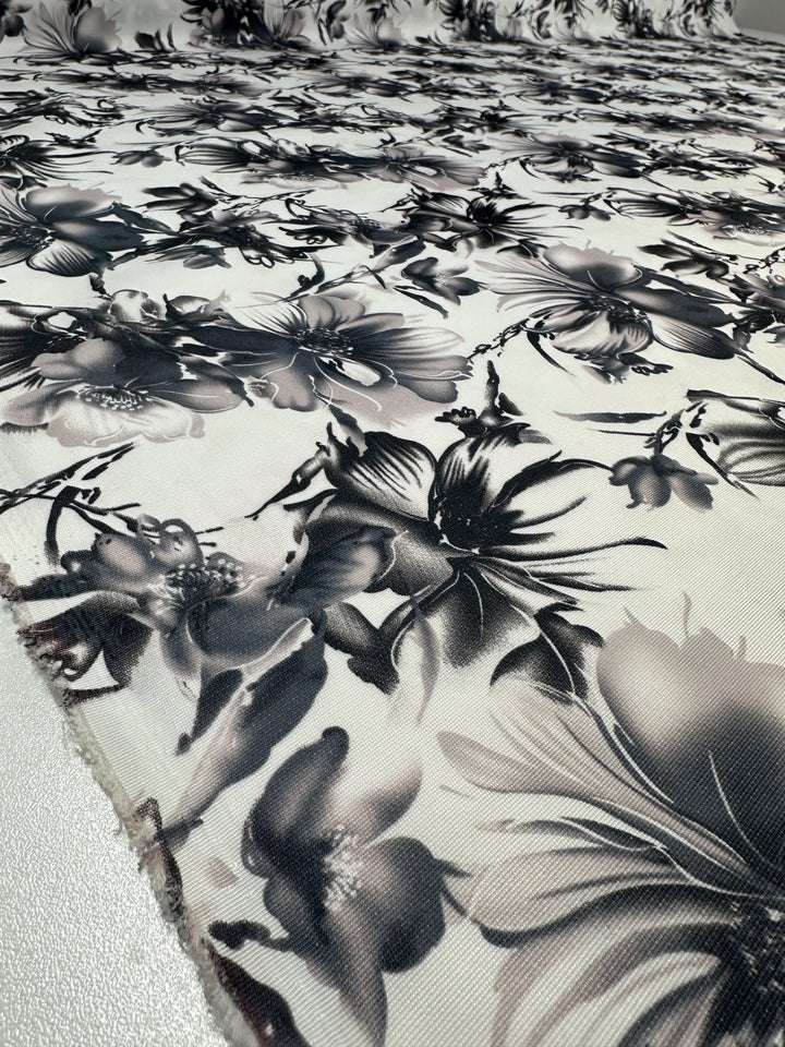 Close-up of Designer Deadstock - Inkveil by Super Cheap Fabrics: a lightweight, textured viscose fabric with bold black and white floral print, large detailed flowers and leaves, shown laid out flat. Width: 145cm.