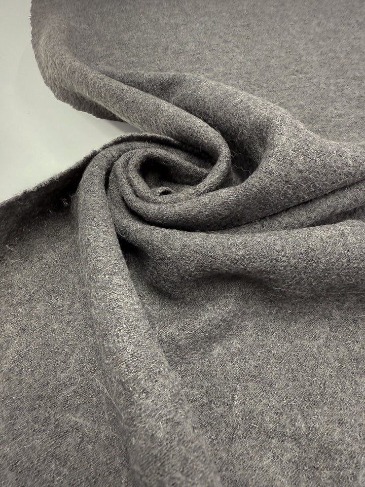 A close-up of Boiled Wool - Ghost Gray - 145cm by Super Cheap Fabrics, featuring its soft, fuzzy texture arranged in a loose spiral—ideal for cozy winter garments.