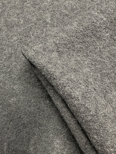 Close-up of Boiled Wool - Ghost Gray (145cm) from Super Cheap Fabrics shows its soft, fuzzy texture and visible fibers. The folded wool-viscose blend creates cozy layers, making it perfect for winter garments.