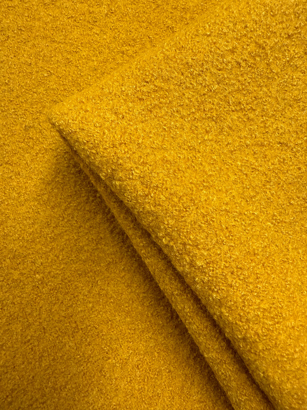 A close-up of Boiled Wool - Mango Mojito (150cm) from Super Cheap Fabrics shows its vibrant yellow, heavy weight texture, neatly folded at the corner with a soft, slightly fuzzy surface.