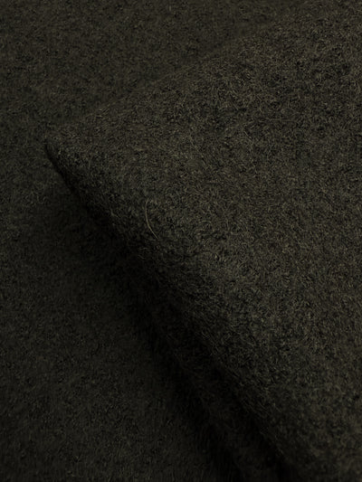 A close-up of Super Cheap Fabrics' Boiled Wool - Forest Night (152cm), featuring a dark brown, textured surface and folded edge—perfect for extra heavy weight winter garments.